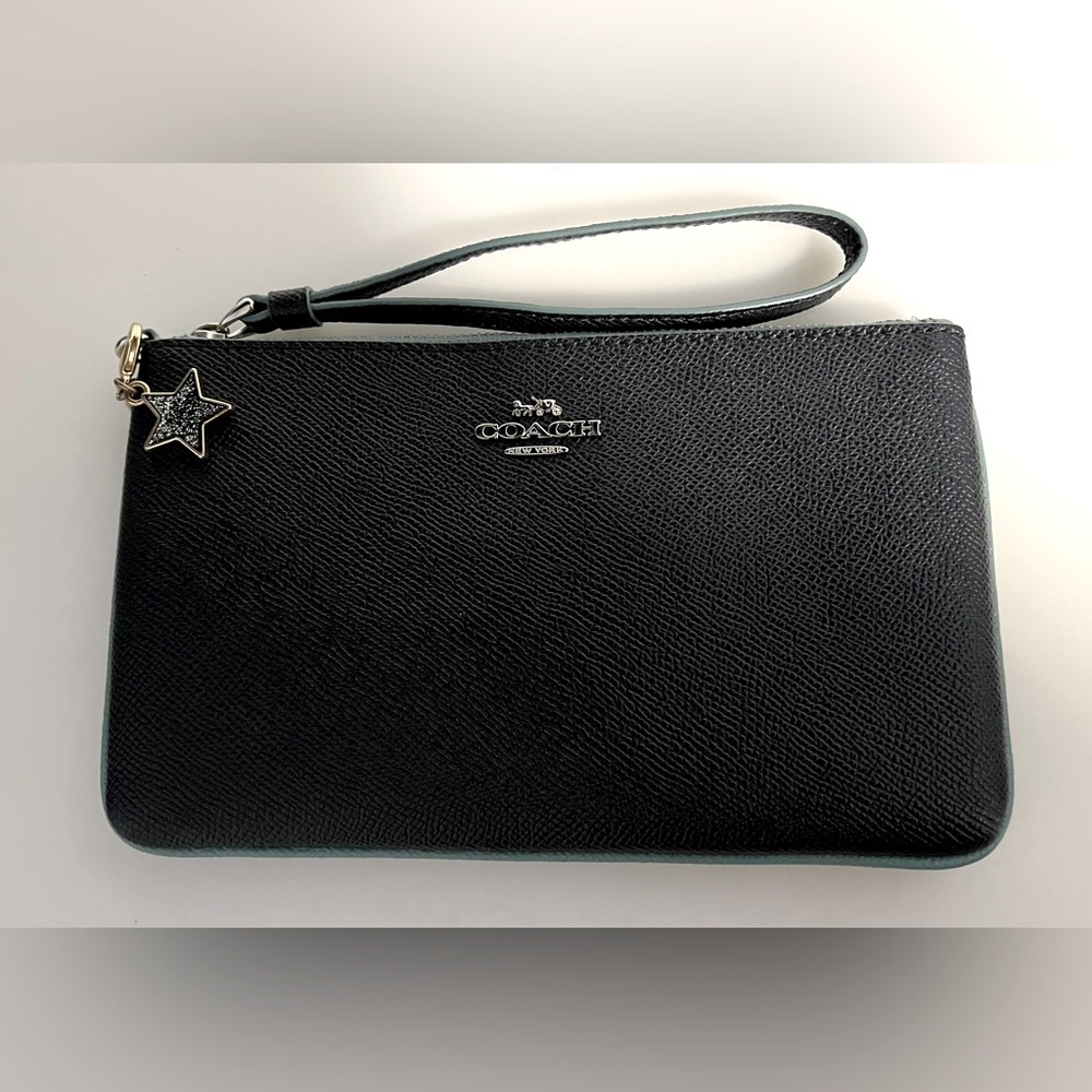 Stylish Coach wristlet in a deep dark blue color with a sleek design.